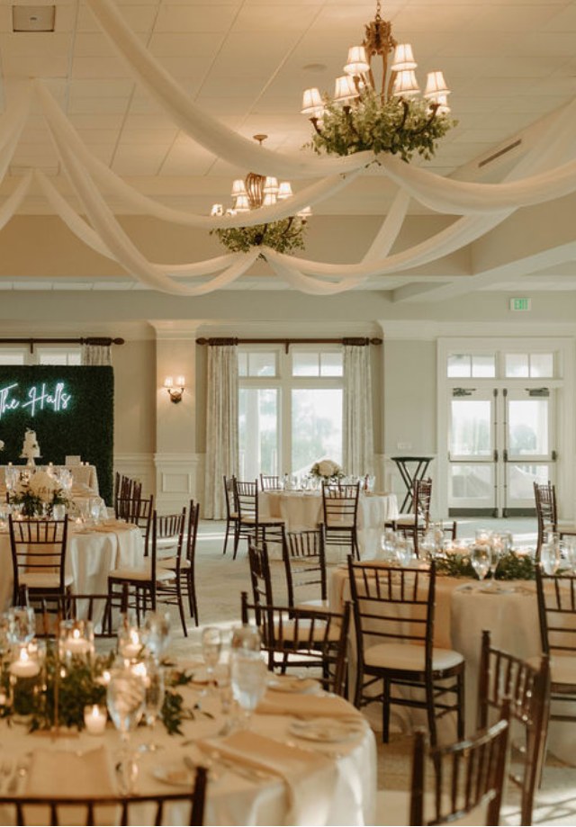 Draped ballroom reception with chandeliers and greenery